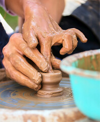 The potter's hands are gently and surely formed by a clay pot on a potter's wheel.