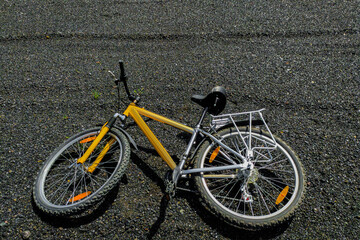 Fototapeta na wymiar Yellow mountain bike lying on loose road surface, no travel concept