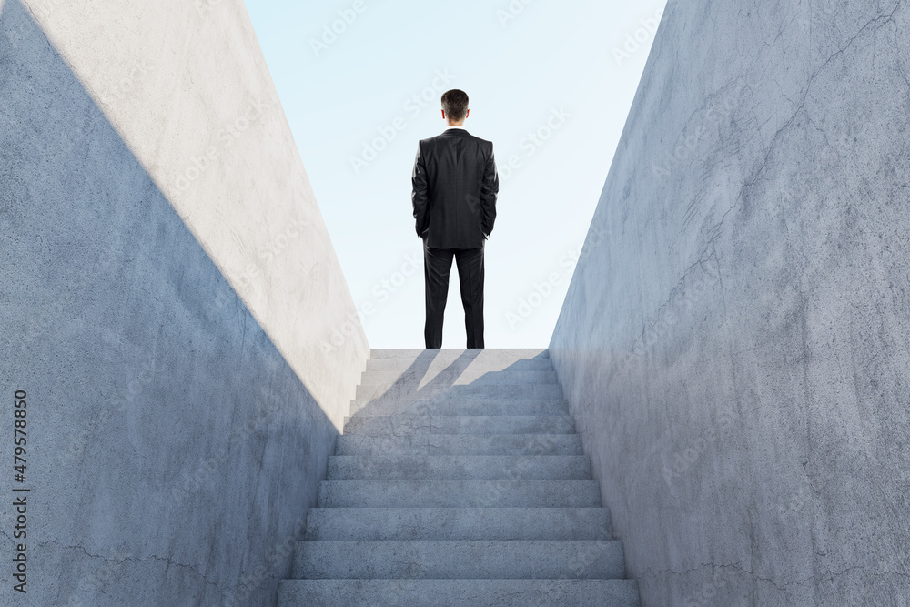 Aufkleber back view of businessman standing on top of abstract concrete stairs to success with sunlight. growt