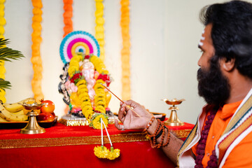Focus on hand Holy god man or Indian priest offering aarti by chanting hymns in front of lord...