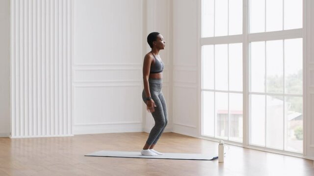 Sporty African American Female Doing Jump Squats Exercise While Training At Home