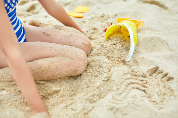 Little kid having fun on the beach and playing with sand toys