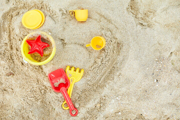 Fototapeta na wymiar Top view, flat lay of scattered plastic beach toys on sand background