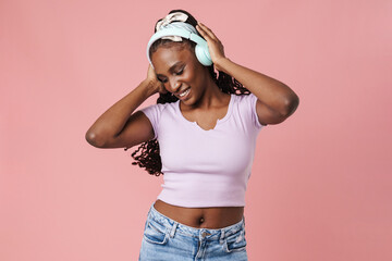 Fototapeta Black young woman smiling while listening music with headphones obraz