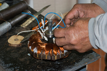 Elderly man winding fan motor, with copper wires in the city of Rio de Janeiro, Brazil.