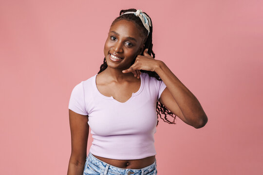Black young woman with pigtails smiling and making call gesture