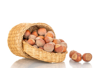 Several organic hazelnuts in a straw basket, close-up, isolated on white.