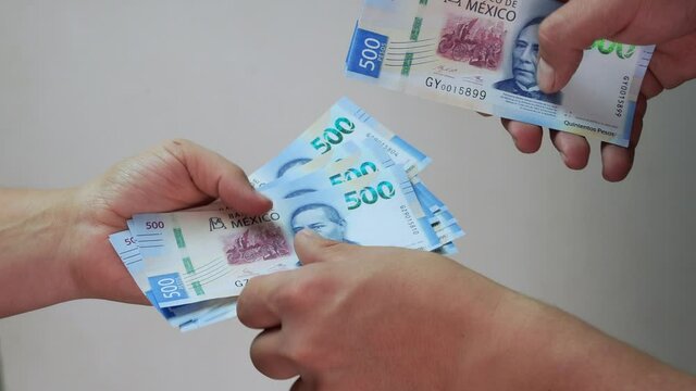 Hombre dando dinero en efectivo a mujer billetes mexicanos 500 pesos haciendo un trato cerrando negocio