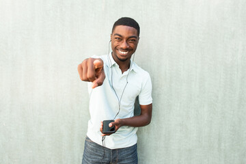 laughing young black man with cellphone and earbuds pointing finger