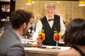 Bartender serving cocktails to a young couple