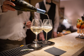 Bartender serving champagne in two glasses