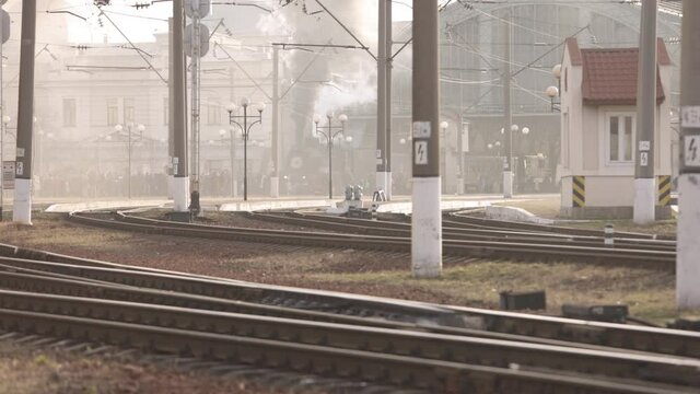 Retro steam train departs from the railway station. Old black steam train with blue cars