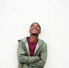 Fototapeta premium young african American man laughing and looking up with arms crossed against white background