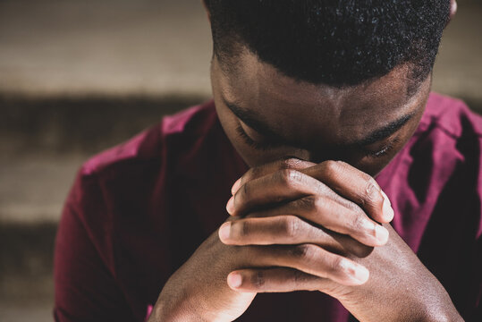 Close up young black man with head in resting in clasp hands