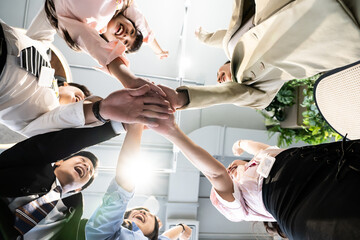 Fototapeta premium Young team putting hands up for new startup in creative office,Cheerful people giving strength motivation,focus on hand,Co-working and teamwork concept,working the job success