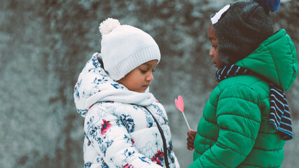 african kids showing love with a heart shaped toy dresses in winter outfit outdoors 
