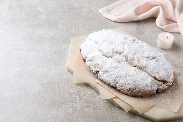 Delicious Stollen sprinkled with powdered sugar on light table. Space for text
