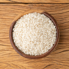 Fototapeta na wymiar Raw carnaroli risotto rice in a bowl over wooden table