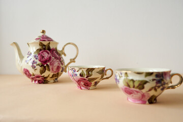 vintage teapot and cups  on white and  peachy background
