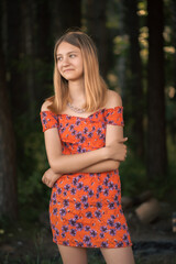Fototapeta premium Portrait of a young beautiful blonde girl in the park in a red dress.