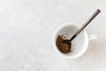 Instant coffee in a spoon in a white mug. View from above. Copy space.