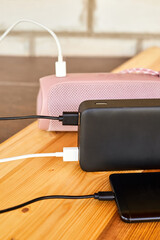 Powerbank charges smartphone and portable speaker using usb. Close-up, selective focus