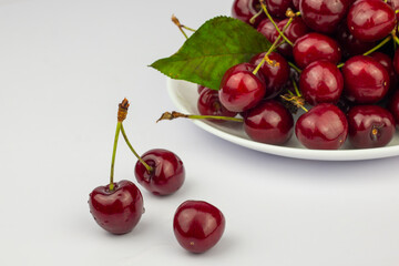 Ripe sweet cherries on a white plate on white background. Close up image.