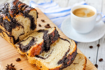 Homemade poppy roll with a cup of coffee on wooden background. Close-up, selective focus