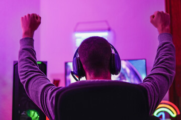 Young boy playing video games and holding hands in the air for celebrating the win