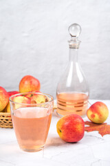 Close-up of a glass of apple juice with apples on a light background.