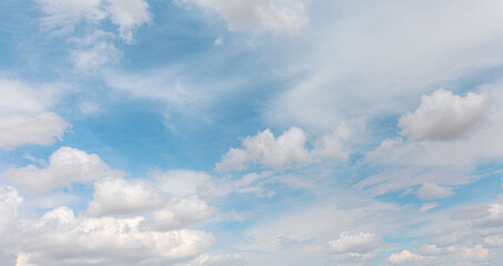 Naklejka na ściany i meble Blue sky and white clouds background - Pillowy clouds cover a blue sky in the background