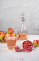 Healthy apple cider vinegar with apples and a centimeter on a light background.