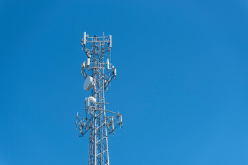 Parte alta de una torre celular con antenas satelitales con el cielo azul