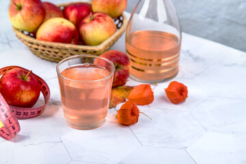 Close-up of a glass with apple cider vinegar and an apple with a measuring tape.