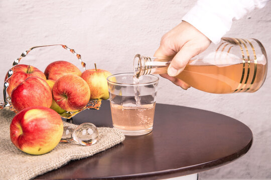 A Woman's Hand Pours Apple Cider Vinegar Into Glasses.