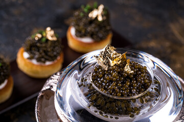 pancakes with black caviar and gold leaf on a background of old wooden surfaces