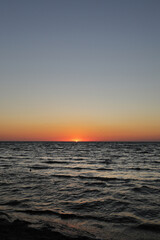 Obraz premium golden sunset or sunrise at the deep dark ocean. aerial view of sundown and up to the sea. yellow and orange colorful sky. romantic beautiful sky in the spring season.