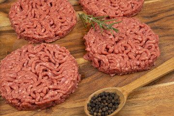 several raw hamburgers on a cutting board