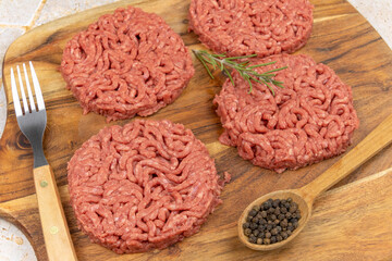 several raw hamburgers on a cutting board