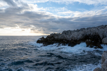 Fototapeta na wymiar Paysage marin du rivage méditerranéen au Cap de Nice en hiver avec des vagues et des rochers au coucher du soleil
