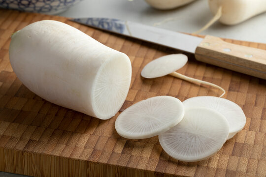Fresh white daikon radish and slices on a cutting board close up 