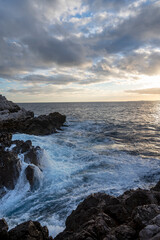 Fototapeta na wymiar Paysage marin du rivage méditerranéen au Cap de Nice en hiver avec des vagues et des rochers au coucher du soleil