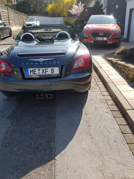 HEILIGENHAUS, NRW, GERMANY - MARCH 28, 2020:
A Hyundai Kona SUV and Chrysler Crossfire Roadster park in front of a house