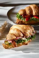 Croissant sandwich - bavarian sausage and lettuce and cream cheese. Sunshine with deep shadows