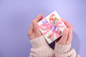 Woman hands hold cute gift box, high-colored Valentine day background with pink colored champagne...