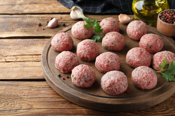 Many fresh raw meatballs on wooden table