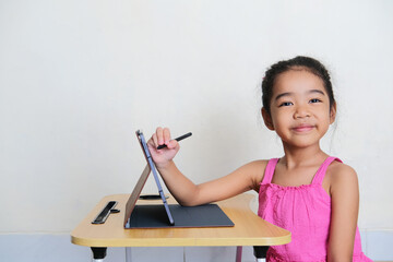 Asian kid smiling happy while drawing using mobile tablet gadget