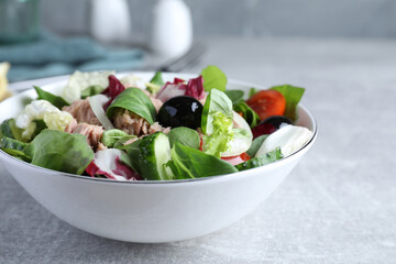 Bowl of delicious salad with canned tuna and vegetables on light grey table