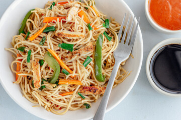 Simple Chicken Chow Mein in a Bowl with Scallion, Cilantro and Condiments on White Background Top Down Close UpPhoto
