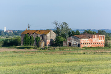 Fototapeta na wymiar A couple of old abandoned, dilapidated buildings in a field in the Italian countryside 